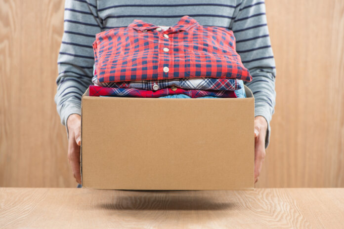 Donation box for poor with clothing in male hands