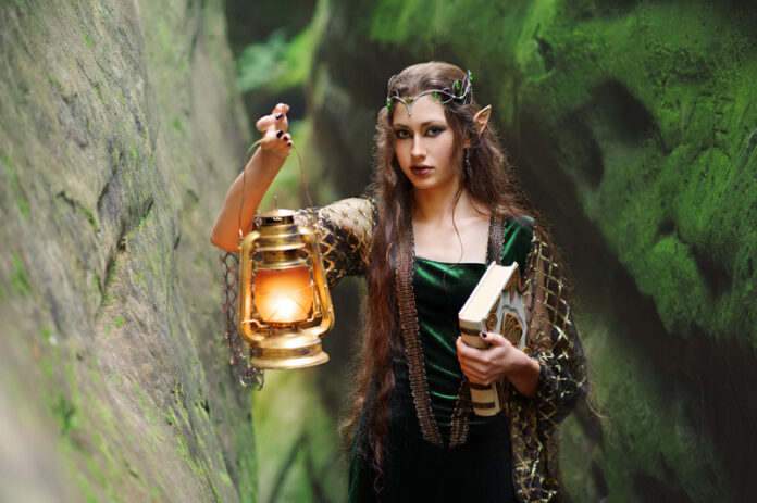 Young beautiful female elf walking through the forest with a boo