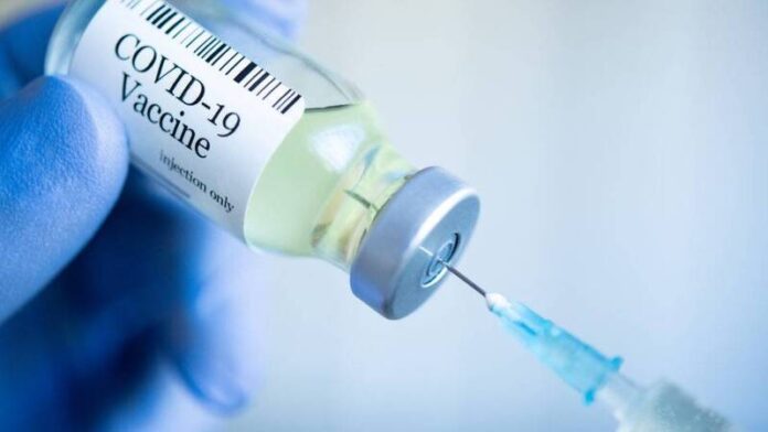 Doctor drawing up Covid-19 vaccine from phial bottle and filling