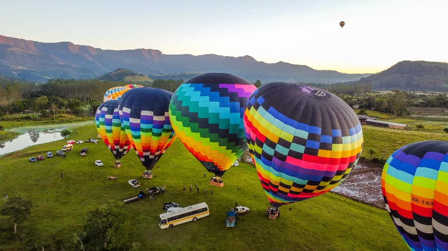 ANAC inicia regulamentação de voos de balão no Brasil Balões de ar quente, grandes e coloridos, sendo inflados em um campo gramado em Praia Grande, em contexto da regulamentação de voos pela ANAC.