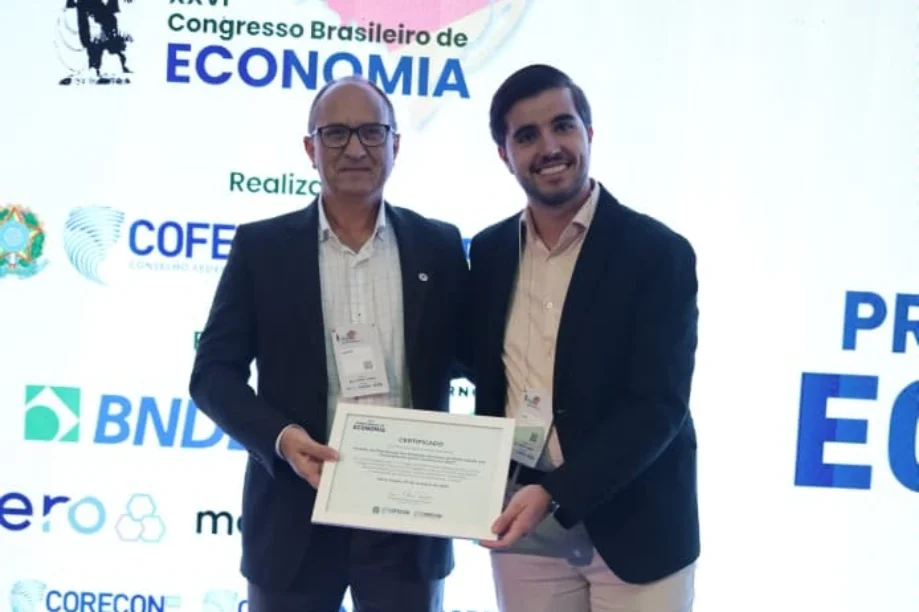 Entrega do prêmio de 1º lugar no Prêmio Brasil de Economia para o aluno da UNESC, com o certificado em destaque.