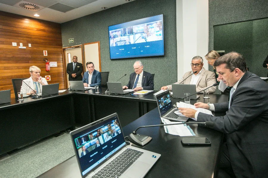 Alesc aprova Cordão de Girassol para deficiências não aparentes Sessão de comissão na ALESC com parlamentares sentados à mesa, onde foi aprovada a lei do Cordão de Girassol para identificação de deficiências não aparentes.