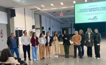 Araranguá se capacita para avaliação de TEA em Turvo Equipe de saúde e educação de Araranguá apresentando o Projeto de Matriciamento Infantojuvenil em um palco, durante a capacitação sobre Transtorno do Espectro Autista (TEA) realizada em Turvo.