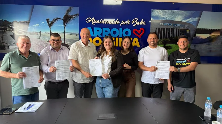 Arroio do Silva assina ordens de serviço para R$ 3 milhões O prefeito Evandro Scaini e outras autoridades em uma mesa, assinando as ordens de serviço para a pavimentação da Rua João Manoel Coelho e o novo Parque Farroupilha.