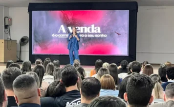 Avança CDL em Sombrio capacita comércio com foco em vendas Vista da plateia de costas, assistindo à palestrante em evento de capacitação para o comércio de Sombrio, com o tema 'A venda é o caminho para o seu sonho'.