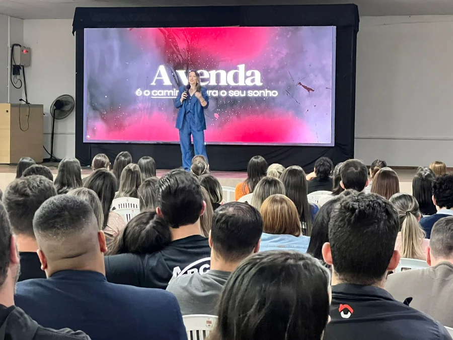 Avança CDL em Sombrio capacita comércio com foco em vendas Vista da plateia de costas, assistindo à palestrante em evento de capacitação para o comércio de Sombrio, com o tema 'A venda é o caminho para o seu sonho'.