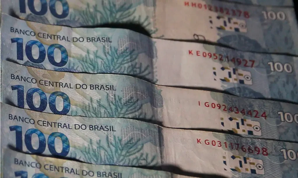 Bolsa Família Pagamento de outubro para NIS final 6 é liberado Feixe de notas de R$ 100 Reais, ilustrando o pagamento do benefício Bolsa Família liberado para o NIS final 6 em outubro.