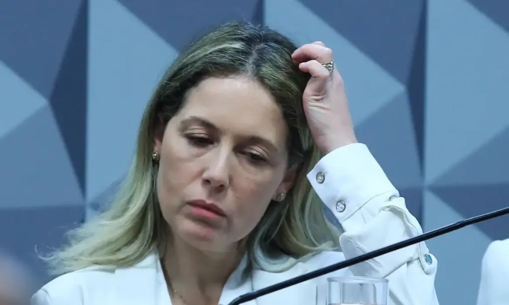 CPMI Esposa de ex-procurador do INSS fica em silêncio Thaisa Hoffmann Jonasson, esposa de ex-procurador do INSS, com a mão na cabeça e expressão séria, durante depoimento na CPMI do INSS onde se negou a responder perguntas.