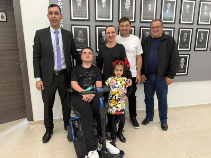 Câmara de Araranguá aprova anteprojeto de acessibilidade O estudante cadeirante Gustavo Zilli Presa no hall da Câmara de Vereadores de Araranguá, sorrindo ao lado do vereador Márcio Mano, que o usou como inspiração para o Anteprojeto de Lei.