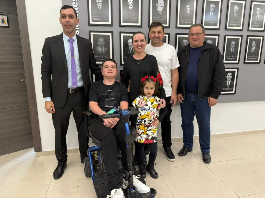 O estudante cadeirante Gustavo Zilli Presa no hall da Câmara de Vereadores de Araranguá, sorrindo ao lado do vereador Márcio Mano, que o usou como inspiração para o Anteprojeto de Lei.