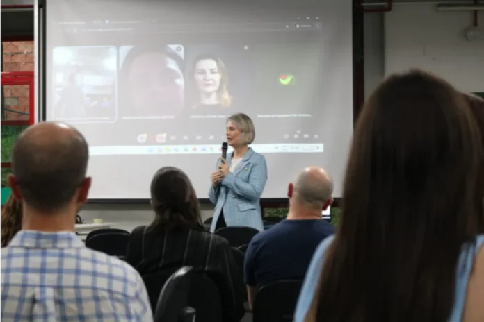 Capes Unesc prepara programas para nova avaliação A reitora em exercício da Unesc, Gisele Silveira Coelho Lopes, e outros gestores em uma mesa de reunião com diversos professores e coordenadores de programas de Pós-Graduação.
