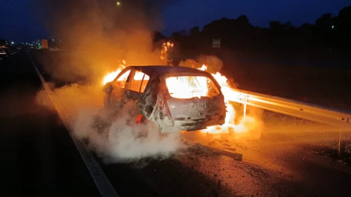 Carro é totalmente destruído por incêndio na BR-101 em Içara Carro em chamas e totalmente destruído, parado na lateral da BR-101 em Içara durante a noite, com grande volume de fogo e fumaça.
