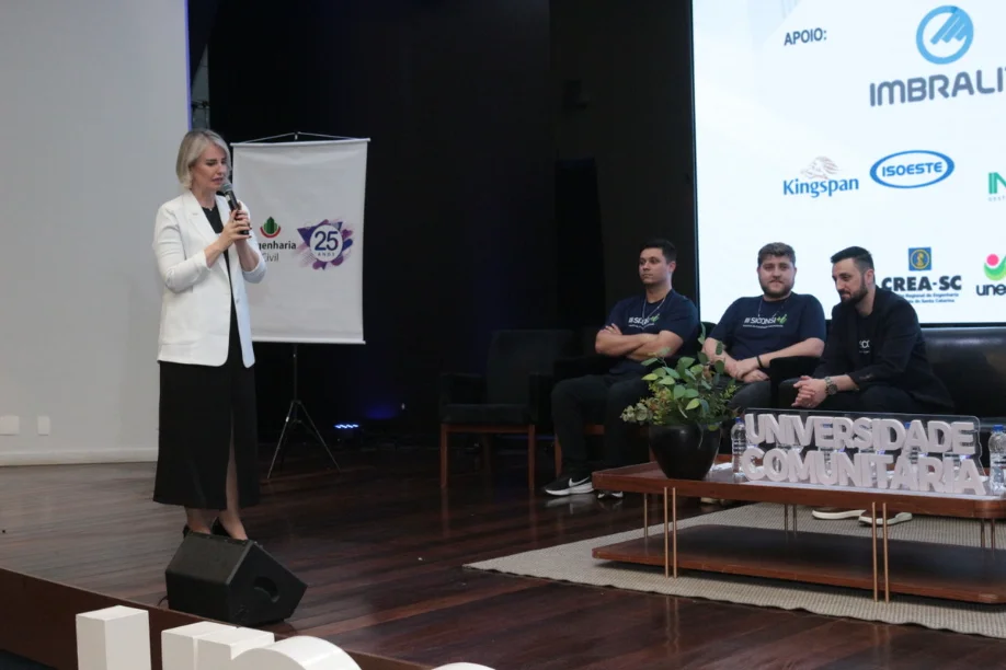 Construção 4.0 Simpósio da Unesc debate madeira e eficiência Reitora da UNESC discursando no palco durante o Simpósio Construção 4.0, onde se debate a eficiência e o uso da madeira na construção civil em Criciúma.