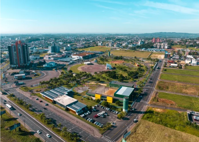 Criciúma celebrará 100 anos com programação histórica e momentos de emoção Vista aérea da cidade de Criciúma em um dia ensolarado, mostrando a área urbana, prédios e o Parque Centenário ao centro, em celebração aos 100 anos do município.
