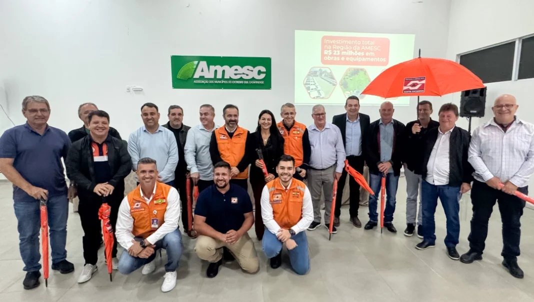Defesa Civil de SC libera R$ 10,7 milhões para obras na AMESC Prefeitos da AMESC e o Secretário de Estado da Defesa Civil (colete laranja) reunidos, segurando guarda-chuvas do órgão, após o anúncio de R$ 10,7 milhões para obras e prevenção no Extremo Sul Catarinense.