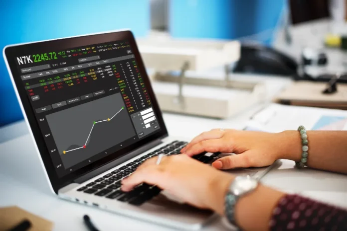Dólar cai e Ibovespa bate recorde após reunião Lula-Trump Mulher analisa dados financeiros e gráficos de mercado de ações em um laptop.