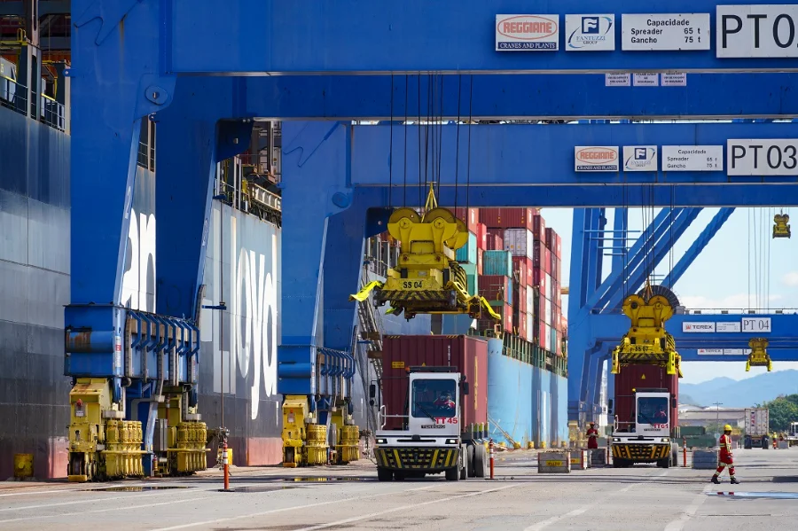Containers empilhados em um porto movimentado de Santa Catarina, com navios ao fundo, simbolizando o forte volume de exportações do estado.