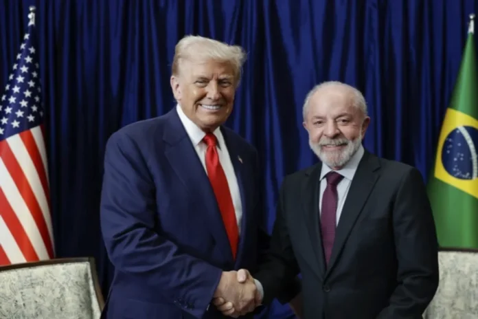 FIESC vê avanço em negociação com os EUA sobre tarifas Donald Trump e Luiz Inácio Lula da Silva apertando as mãos com bandeiras dos EUA e do Brasil ao fundo, simbolizando o avanço na negociação de tarifas comerciais vista pela FIESC de Santa Catarina.