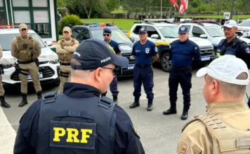 Festas de Outubro: Forças de segurança se unem contra acidentes Policiais de diversas corporações, incluindo PRF (Polícia Rodoviária Federal), Polícia Militar e Polícia Civil, reunidos para briefing em frente às viaturas, em ação de segurança conjunta para as Festas de Outubro.
