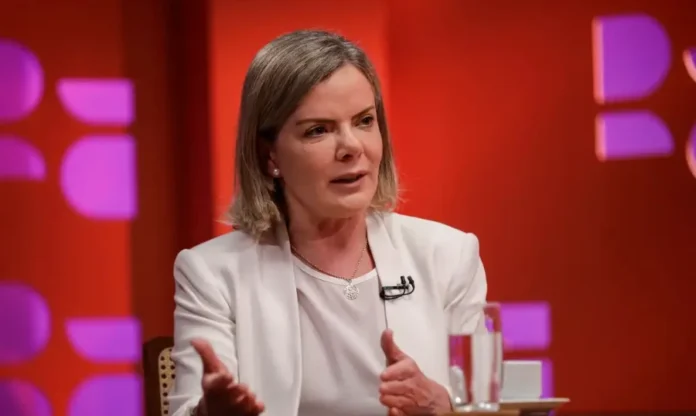 Gleisi critica “Consórcio da Paz” de governadores de direita Ministra Gleisi Hoffmann, vestindo blazer branco, discursando em entrevista, criticando a aliança de governadores de direita (Consórcio da Paz) e seu impacto na política nacional.