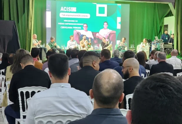 Empresários e convidados assistindo a um talk-show com palestrantes no palco do IV Fórum Empresarial ACIS em Sombrio, debatendo empreendedorismo.