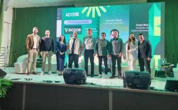 IV Fórum Empresarial ACIS 2025 reúne empresários em Sombrio Painel de convidados e palestrantes no palco, com a logo da ACIS e informações sobre SICOOB e UNESC, durante o IV Fórum Empresarial em Sombrio.