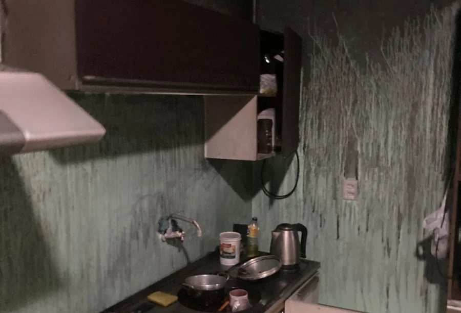 Cozinha de uma kitnet em Araranguá após incêndio, com paredes e armários visivelmente manchados de fuligem e fumaça.