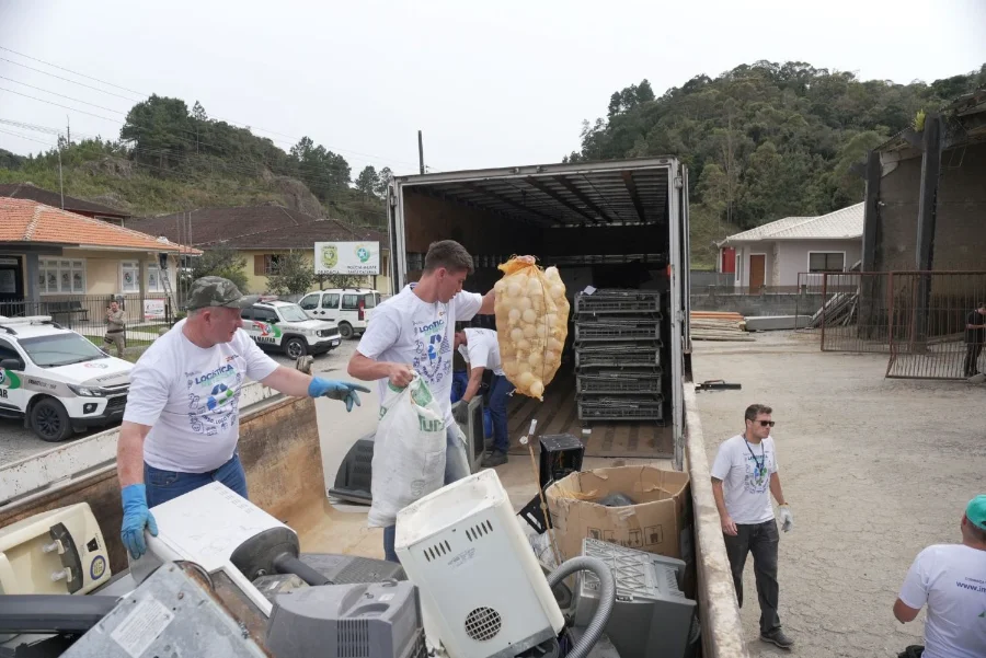 Ação de coleta do Programa de Logística Reversa (PLD) de SC, com voluntários recolhendo equipamentos descartados para reciclagem.