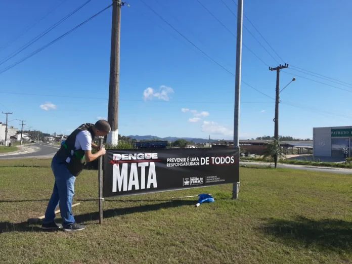 Morro da Fumaça reforça alerta contra dengue em Finados Funcionário instalando a faixa de alerta "Dengue Mata - Prevenir é uma responsabilidade de todos" em Morro da Fumaça, reforçando a campanha de prevenção no feriado de Finados.