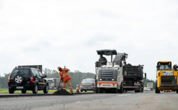 Obras na BR-101 terão interdição parcial de faixas marginais Trabalhadores e máquina pavimentadora (Wirtgen) em obra de recapeamento na BR-101, com interdição parcial das faixas marginais e carros passando ao lado.