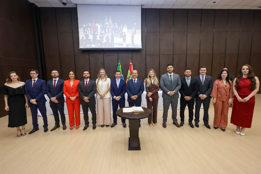 Procuradoria-Geral de SC ganha reforço com 12 novos nomes Grupo de 12 novos procuradores e procuradoras em frente a bandeiras e a um telão, durante a cerimônia de posse na Procuradoria-Geral do Estado de Santa Catarina (PGE/SC).