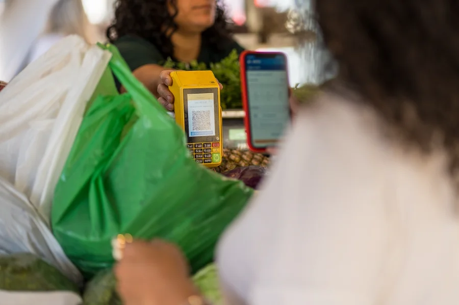 Uma pessoa (consumidor) realiza uma compra em um stand ou loja de um pequeno empreendedor, com foco na interação de negócios e apoio ao empreendedorismo.