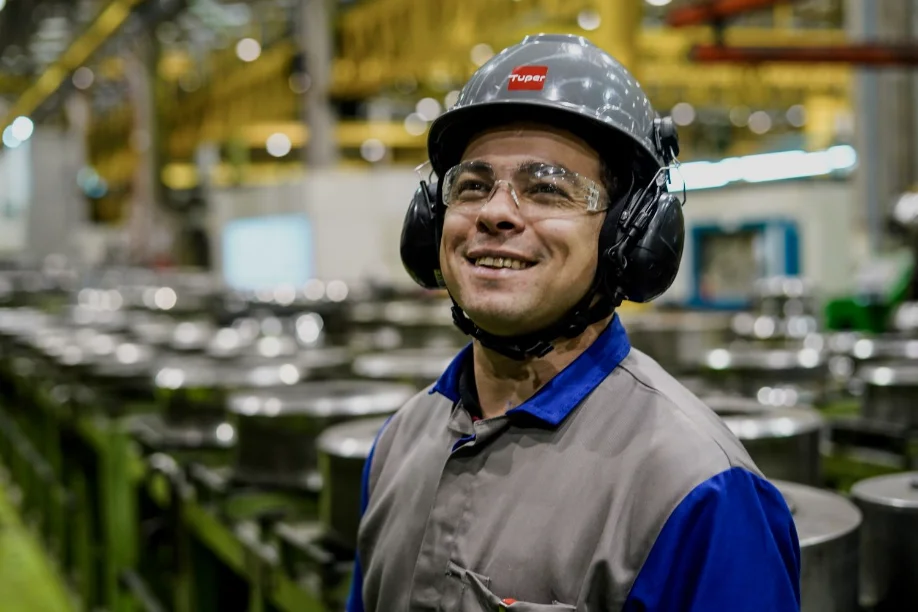 Homem em uniforme de fábrica, usando equipamentos de segurança, representando a força de trabalho da indústria em Santa Catarina.