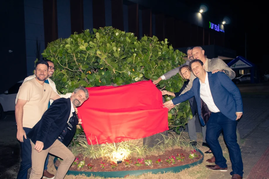 Autoridades e investidores descerram uma placa vermelha sobre uma planta, marcando o lançamento do futuro Hospital Oncológico de Araranguá.