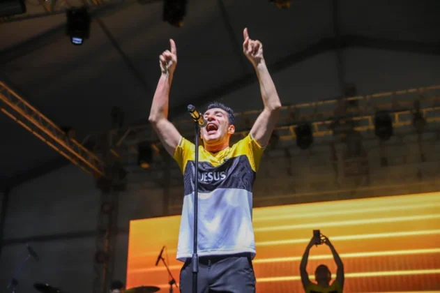 O cantor gospel Leandro Borges no palco do Parque das Nações, em Criciúma, se apresentando para uma multidão de aproximadamente 20 mil pessoas durante a celebração do centenário.