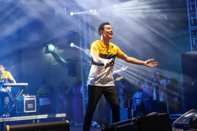O cantor gospel Leandro Borges no palco do Parque das Nações, em Criciúma, se apresentando para uma multidão de aproximadamente 20 mil pessoas durante a celebração do centenário.