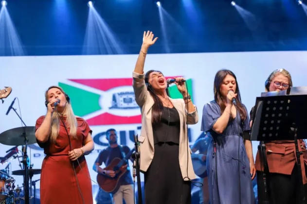 O cantor gospel Leandro Borges no palco do Parque das Nações, em Criciúma, se apresentando para uma multidão de aproximadamente 20 mil pessoas durante a celebração do centenário.