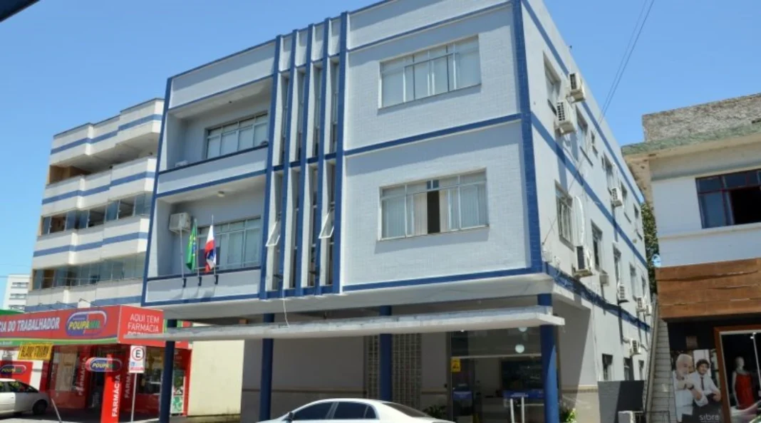 Siderópolis abre processo seletivo para professores e auxiliares Edifício de cor azul e branca no centro de Siderópolis, sede da administração municipal que realiza o processo seletivo.