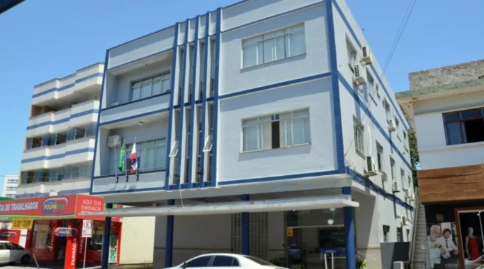 Siderópolis abre processo seletivo para professores e auxiliares Edifício de cor azul e branca no centro de Siderópolis, sede da administração municipal que realiza o processo seletivo.