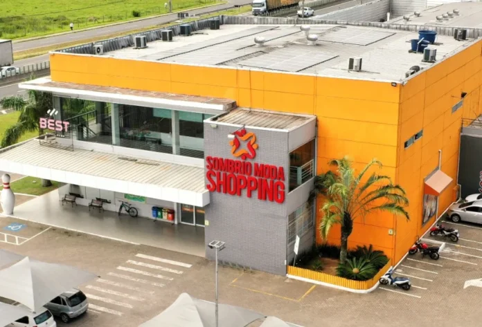 Sombrio Moda Shopping terá pedal e Ritbox no Outubro Rosa Vista aérea da fachada moderna e laranja do Sombrio Moda Shopping, onde serão realizados eventos de Pedal e Ritbox no Outubro Rosa.