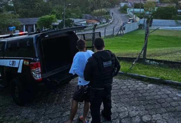 Homem preso pela Polícia Civil sendo conduzidos após operação de combate ao tráfico nos bairros de Criciúma e Siderópolis.