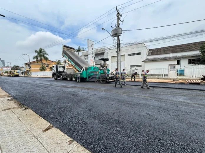 Trânsito no Centro de Araranguá será alterado para obras Caminhão basculante descarregando asfalto em máquina de pavimentação em uma rua do Centro de Araranguá, sinalizando a obra que altera o trânsito.