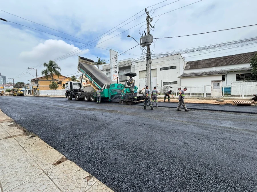 Trânsito no Centro de Araranguá será alterado para obras Caminhão basculante descarregando asfalto em máquina de pavimentação em uma rua do Centro de Araranguá, sinalizando a obra que altera o trânsito.