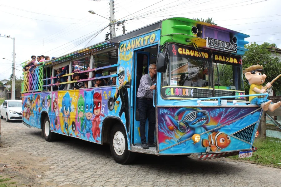 Trenzinho da Alegria (ônibus colorido com desenhos animados e passageiros) percorrendo um bairro em Criciúma, levando festa gratuita à comunidade.