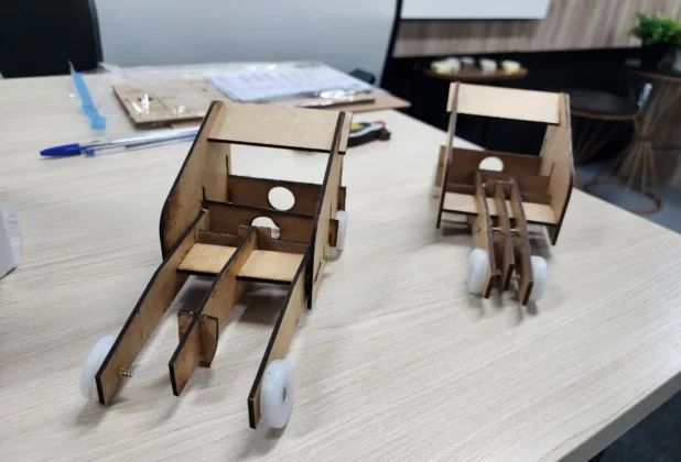 Protótipos de carros em miniatura, feitos de madeira e peças de encaixe, prontos para a competição "Ciência da Velocidade" sediada pela UNESC Araranguá.