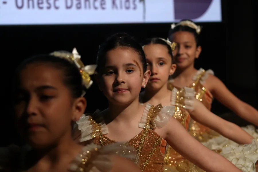 Unesc Dance Kids celebra Dia das Crianças com 300 bailarinos Grupo de bailarinas mirins, vestindo figurinos brilhantes dourados, se apresentando no evento Unesc Dance Kids, em Criciúma.