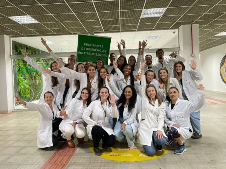 Unesc abre 36 vagas para Residência Multiprofissional Profissionais de diferentes áreas da saúde, incluindo enfermeiros e psicólogos, reunidos em um hospital ou unidade de saúde, simbolizando a Residência Multiprofissional.
