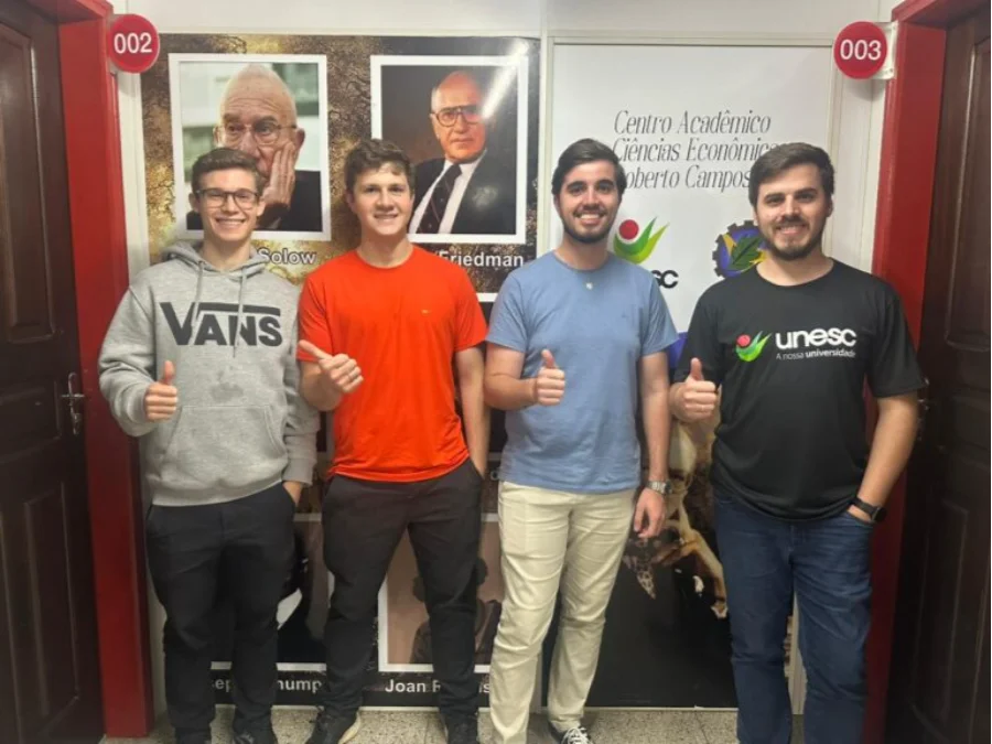 Os quatro acadêmicos do curso de Ciências Econômicas da Unesc, Erick, Isaías, Luiz Gustavo e Eduardo, posando juntos com certificados ou troféus, celebrando a classificação para a etapa nacional da gincana.