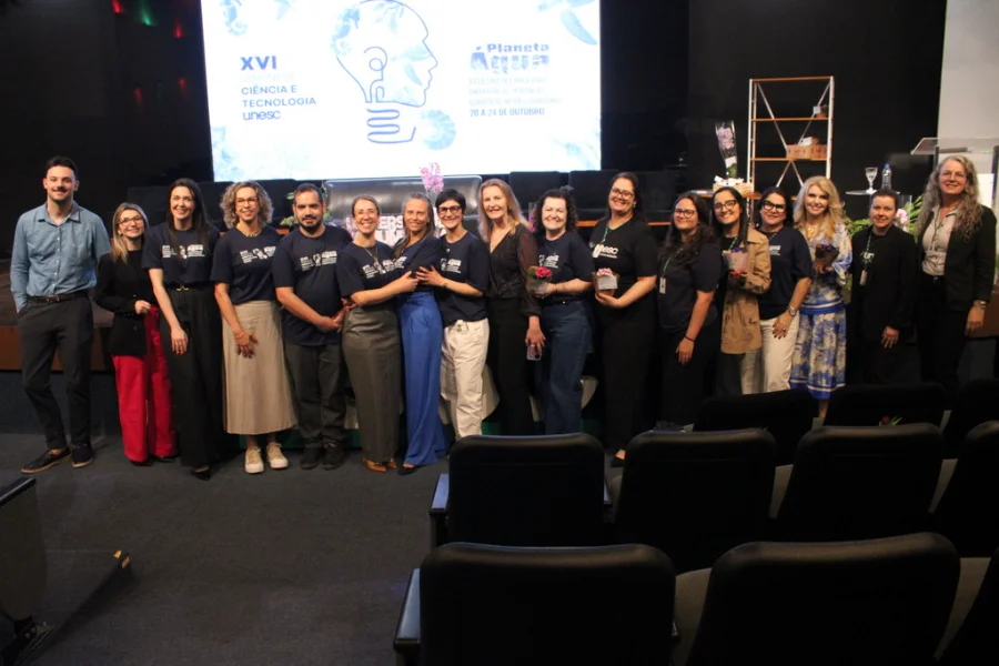 Unesc encerra SCT 2025 com 2,8 mil envolvidos e balanço positivo Equipe de organizadores e professores da UNESC posando para foto no palco, celebrando o encerramento da 16ª Semana de Ciência e Tecnologia (SCT), que envolveu 2,8 mil pessoas em Criciúma.