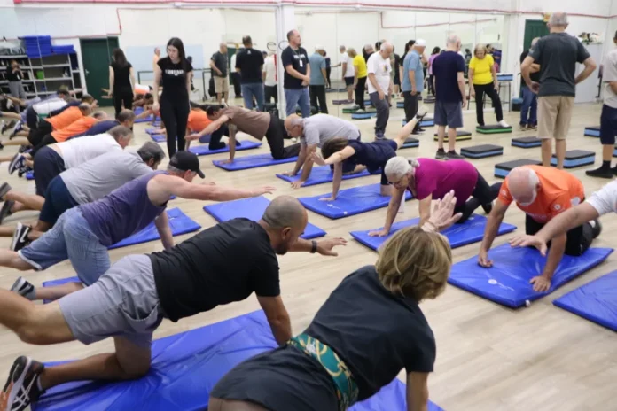 Unesc faz estudo pioneiro com Cannabis para Parkinson Pessoas com Doença de Parkinson realizando exercícios de fisioterapia em grupo, em colchonetes azuis, como parte do estudo pioneiro da UNESC (Criciúma) sobre Cannabis medicinal e exercício físico.